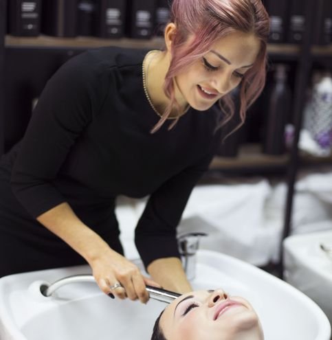 Gorgeous cheerful young woman enjoying head massage while getting her hair washed by a professional hairdresser.  Beauty care, hairstyling, fashion, lifestyle glamour concept